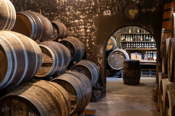 Aging process of cognac spirit in old French oak barrels in cellar in distillery in Cognac white...