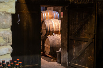 Aging process of cognac spirit in old French oak barrels in cellar in distillery in Cognac white...