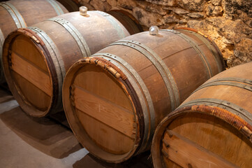Wine cellar with wooden barrels in old wine domain on Sauternes vineyards in Barsac village...