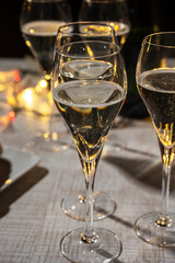 New year party, small bubbles of brut champagne cava or prosecco wine in tulip glasses with garland  lights on background