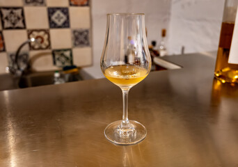 Tasting of cognac spirit aged in old French oak barrels in cellar in distillery in Cognac white...