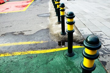 This metal road divider in the form of a pole with a semi circular top painted green with a...