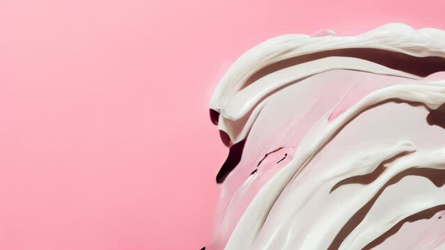 White cream randomly spread on a pink background, evoking use as a texture for beauty and cosmetics
