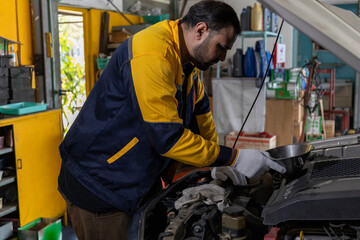 Professional Uniformed Car Mechanic Working in Service Station. Repairing Vehicle. Car's Engine in The Uniform Works in The Automobile Salon. Selective Focus