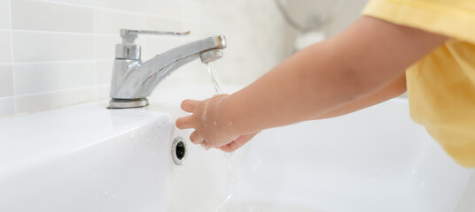 little kid hands wash with soap bubbles and rinse with clean water to prevent and stop the spread...