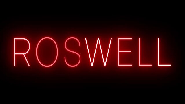 Flickering red retro style neon sign glowing against a black background for ROSWELL