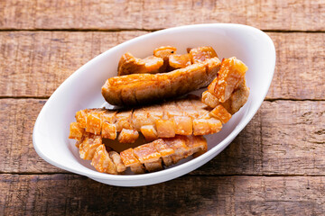 pork belly or pork rinds in a white container on old wood, traditional Colombian food