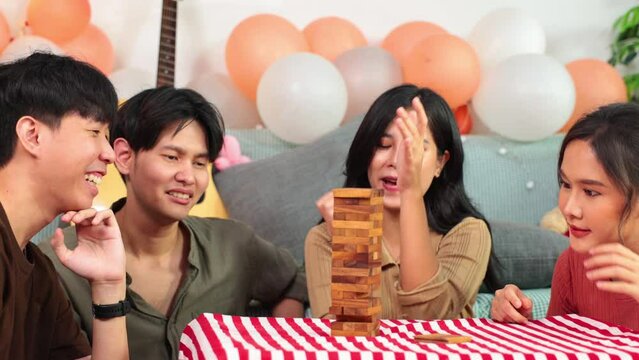Jenga or Tumble tower wooden block game. Young happy people playing Jenga game at home