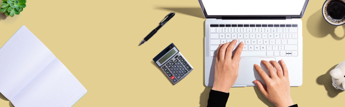 Woman using a laptop computer with a piggy bank and a calculator