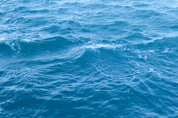 The ocean is calm and the waves are small. The water is a beautiful shade of blue. The sky is clear and the sun is shining