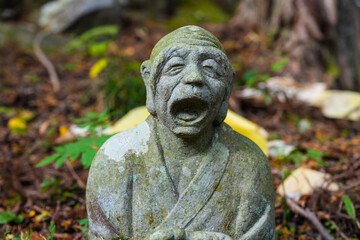 Moss covered stone Buddhist monk carving with open mouth