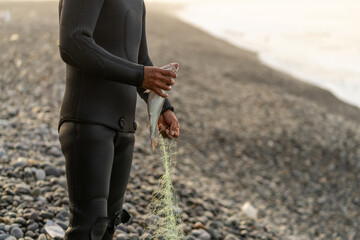 Fisherman in wetsuit removing a trapped fish from the net