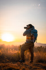  The photographer, camera in hand and backpack on his back, celebrates the encounter with the sun over the majestic mountains adventurer concept, local travel,