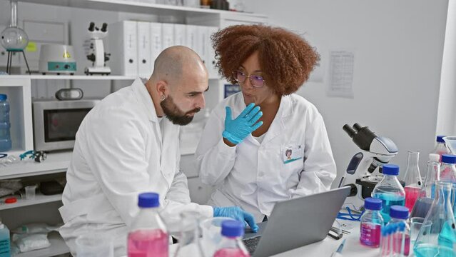 In a heartwarming moment, two jubilant scientists high five in the lab, celebrating a breakthrough over their laptop, embodying the spirit of teamwork and scientific achievement.