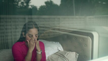 Sad teenage girl crying in bedroom. Shot from outside the room in 4K 50fps video