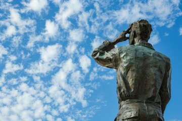 back view of a white marble statue against a backdrop of a bright blue sky with scattered clouds