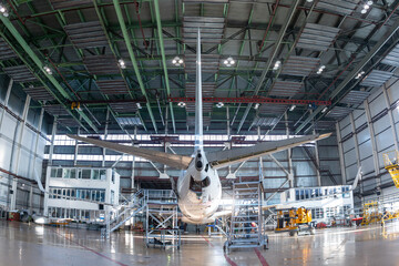 Rear view of a white passenger jetliner in the aviation hangar. Aircraft under maintenance....