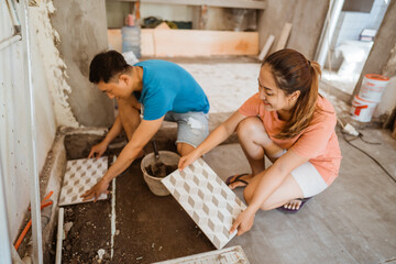 young Asian couple tiling together while renovating their own home