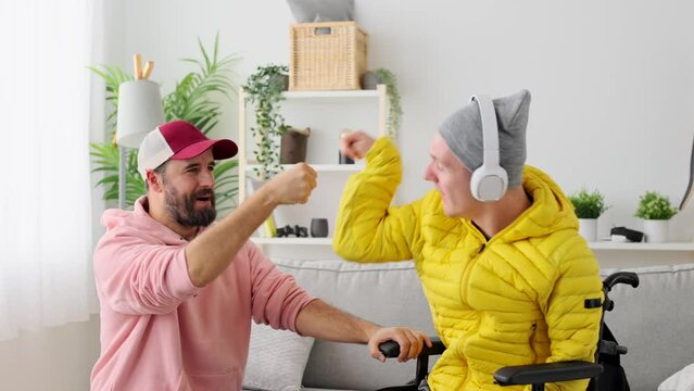 Handicapped man and caregiver doing high five. Person with cerebral palsy having fun at home