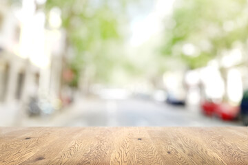 木目のある木製のテーブル越しに見えるボケた背景、奥行きのある背景、街の背景画像