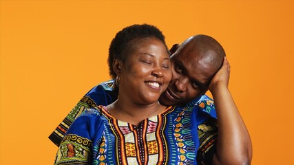 Caring husband hugging his wife in front of camera, showing honest feelings and true love for his life partner. African american couple embracing and presenting their sincere emotions. - obrazy, fototapety, plakaty