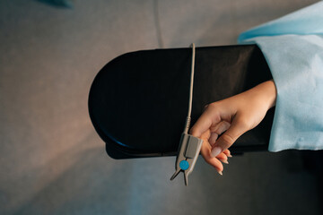 Close-up top view of pulse oximeter on finger of patient during surgery operation. Patient lying on...