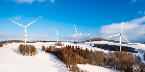 Aerial view of wind turbine farm on the hill in winter sunny day. Production of renewable energy. 