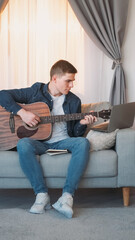 Guitar practice. Online music course. Talented focused man playing song chords on string instrument...