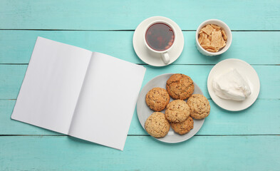 Cup of tea with cookies and notebook on blue table