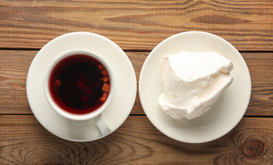 Large piece of meringue and tea cup on a plate, wooden table