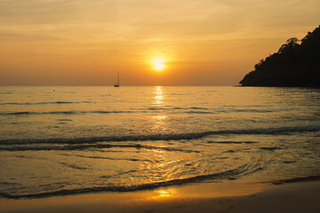 Sunset on the beach with long coastline, sun and dramatic sky. Tropical sea sunset. Sky background. Bright beautiful sunrise or sunset at sea.