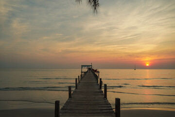 Fototapeta premium beautiful sunset at the wooden jetty at the beach. Wood bridge on the sea which has walk way for travel with beautiful sky and sunshine background.
