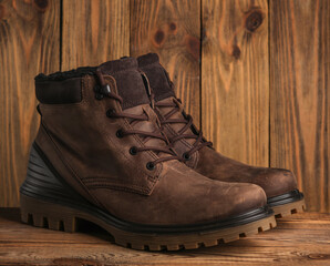 Pair of brown leather boots on wooden background