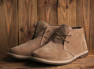 Pair of suede desert boots on a wooden background