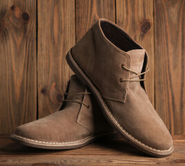 Pair of suede desert boots on a wooden background