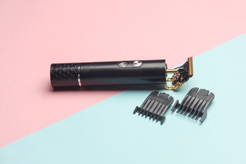 Modern cordless hair trimmer with replaceable attachments on a pink blue background
