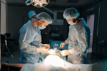 Focused professional surgeons and nurse in uniform at work in operating room, performing heart...