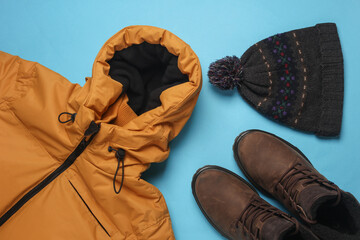 Set of men's winter clothes on blue background. Top view