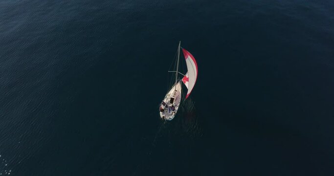 Aerial view. Yacht sailing on open sea at windy day aerial. Sun shine over white sail boat at ocean bay