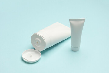 White cream tubes on blue background. Cosmetics