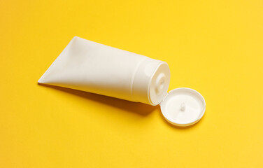White cream tube on yellow background. Cosmetics