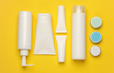 Tubes, bottles and jars of cosmetics on yellow background. Flat lay