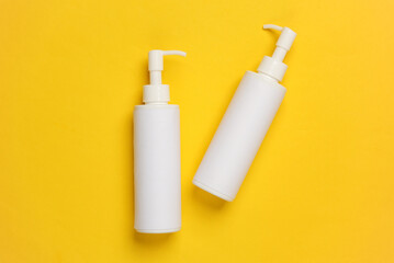 Bottles of cream with dispenser on yellow background