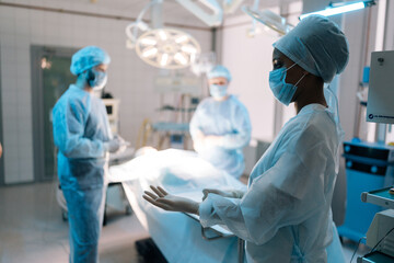 Side view of diverse group surgeons and nurse wearing on disposable gloves as hygiene before...