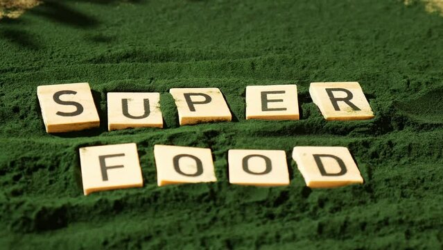 SUPERFOOD letter chlorella on green background of algae superfood. Organic blue-green algae spirulina powder food. Healthy benefits of natural supplement. Alternative medicine mineral food antioxidant