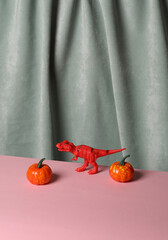 Pumpkins with toy dinosaur against the background of curtain. Aesthetic beauty still life....