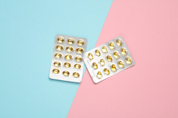 Blisters of fish oil pills on a blue pink background