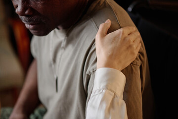 Closeup of hand of caring caucasian woman on shoulder of african american man, sign of moral support