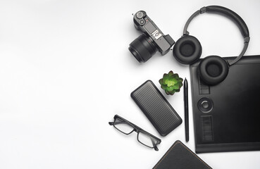 Camera, tablet, power bank, headphones and notepad on white. Modern accessories and gadgets. Working equipment of a photographer or retoucher. Flat lay. Top view