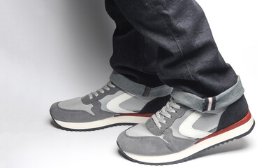 Male legs in jeans and sneakers on a white background